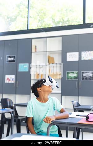 Biracial boy wearing virtual reality headset in a classroom at school Stock Photo