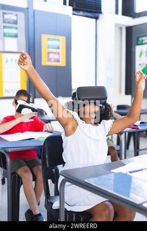 Biracial girl with curly hair is using a VR headset in a classroom at school Stock Photo