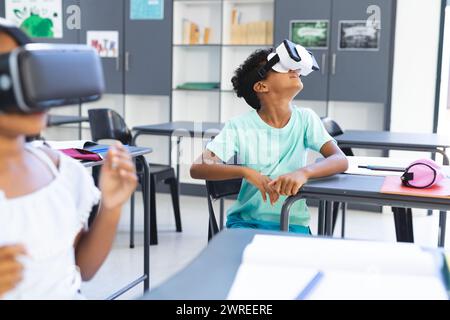 Biracial children explore with VR headsets in a classroom at school Stock Photo