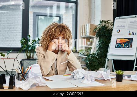 tired curly african american businesswoman at her desk crumpled papers, stress at work concept Stock Photo