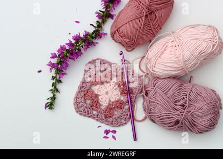 Pink crocheted granny square, soft  cotton yarn balls of different pink color shades. White background with copy space. Spring crochet concept. Stock Photo