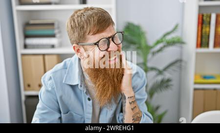 Handsome redhead business worker, a young man sitting in pain at the office table, suffering from toothache Stock Photo
