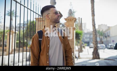 Handsome young hispanic man with a beard, wearing casual clothing, standing on an urban city street. Stock Photo