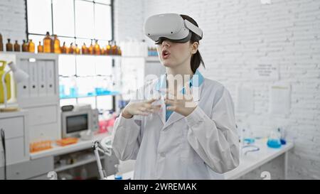 A young woman scientist explores virtual reality in a modern laboratory setting, donning a vr headset amidst lab equipment. Stock Photo