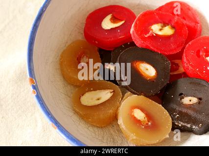 Slices of Cypriot sweetmeat shoushoukos or soutzoukos in a bowl. The red is flavoured with pomegranate, the black with carob. The brown one is the classic original. Stock Photo