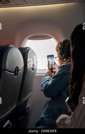 A vertical shot of a young woman taking a photo from an airplane window Stock Photo
