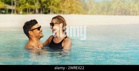 happy couple in love swimming in the ocean by tropical white sand beach. romantic getaway. banner with copy space Stock Photo