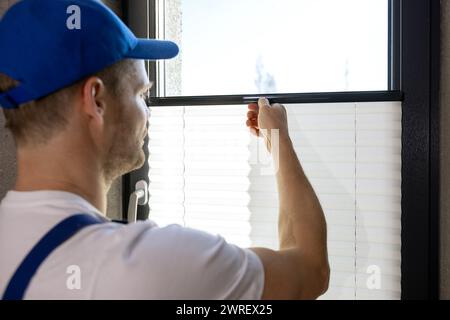 worker installing pleated blinds on the window Stock Photo