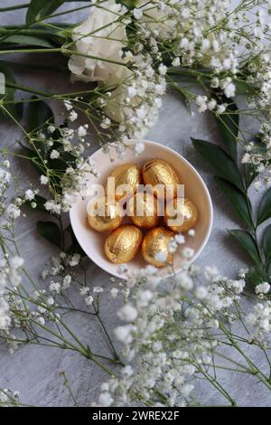 Vibrant colors of Easter sweets. Colorful still life with white gypsophila flowers and chocolate eggs. Stock Photo