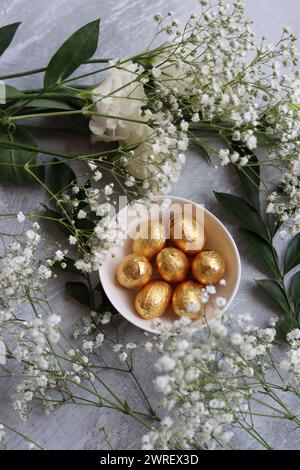 Vibrant colors of Easter sweets. Colorful still life with white gypsophila flowers and chocolate eggs. Stock Photo