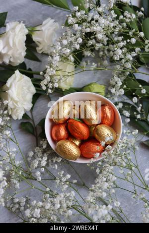 Vibrant colors of Easter sweets. Colorful still life with white gypsophila flowers and chocolate eggs. Stock Photo