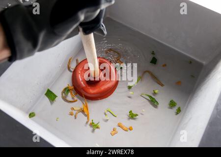 plumber cleans clogged kitchen sink with plunger Stock Photo