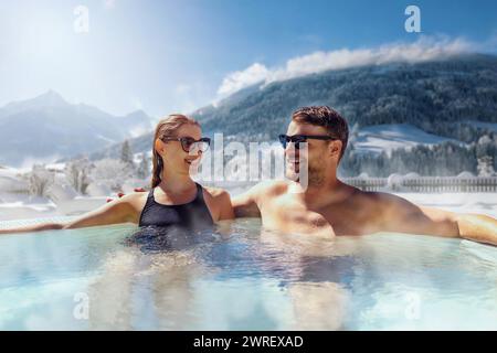 happy couple relaxing in outdoor hot tub at ski spa resort. winter vacation Stock Photo