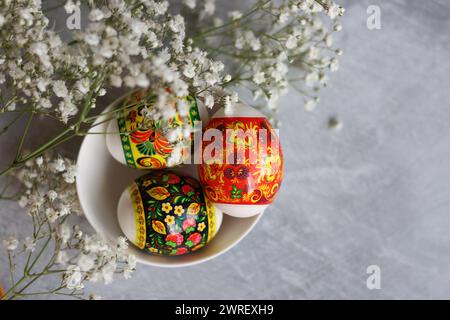 Easter eggs on a table. Still life with white flowers and eggs. Top view photo of colorful eggs on a table. Easter holidays concept. Stock Photo