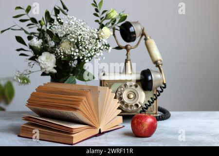 Retro styled still life with an open book on a desk. Close up photo of vintage objects. Stock Photo
