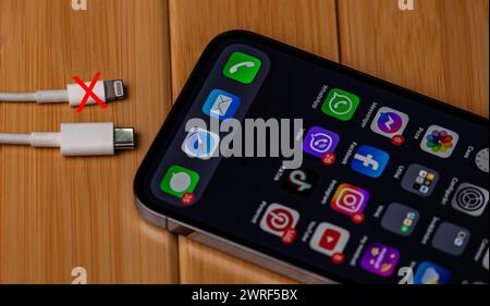 The new generation of charger for iphone type-c, the old charger model being cut with a red x on a wooden background. Moldova,Hincesti 04.09.2023. Stock Photo