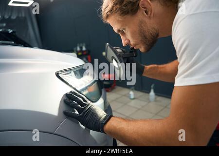 Long-haired man conducts a check inspection of a car body Stock Photo