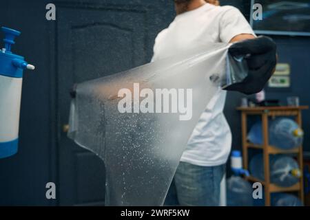 Master holds in his hands anti-gravel film for gluing Stock Photo