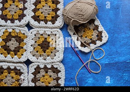 Crochet ornament close up. Granny squares made of natural organic wool yarn. Cozy autumn evening. Hobby and leisure concept. Soft yarn texture Stock Photo
