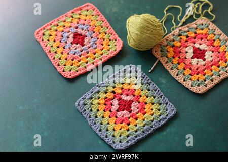 Handmade crocheting, needlework and handicraft concept. Rainbow colored granny squares close up photo. Crochet texture. Stock Photo