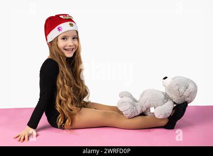 Young girl athlete gymnast with toy bear in hands posing on black background. High quality photo Stock Photo