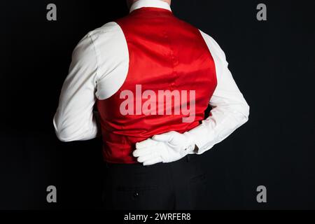 Portrait of Butler or Waiter in Red Vest or Waistcoat and White Gloves Standing At Elegant Attention. Service Industry and Professional Courtesy. Stock Photo