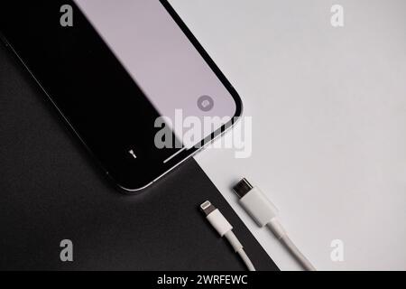 A picture of an iPhone that has a black and white background picture , where the old charger is on the black color and type c on the white color Stock Photo