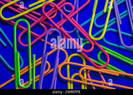 A close-up of colourful paperclips scattered on a blue background Stock Photo