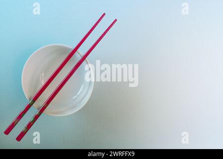 A white ceramic bowl with red Japanese style chopsticks Stock Photo