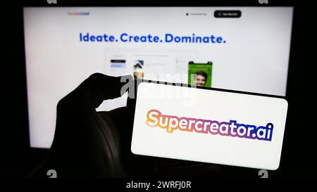 Person holding mobile phone with logo of US artificial intelligence video app company Supercreator in front of web page. Focus on phone display. Stock Photo