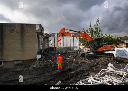 Demolition site (man in hi-vis working hosing rubble, building deconstruction, controlled collapse, empty shell) - Baildon, West Yorkshire England UK. Stock Photo