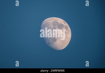 Clear view of the moon's surface during the waxing gibbous phase against a twilight sky Stock Photo