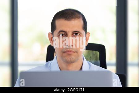 Shot of a mature businessman working at his computer and looking at camera in an office Stock Photo