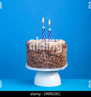 Birthday celebration with candle - Chocolate cake on blue background Stock Photo