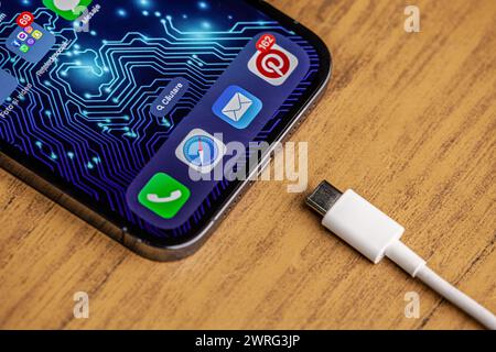 A picture of the new iPhone 15 with the new charger on a wooden background and artificial intelligence technology background.Hincesti,Moldova,11.09 Stock Photo