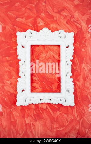 white cement baroque frame on red painted background with visible brushstrokes, close up Stock Photo