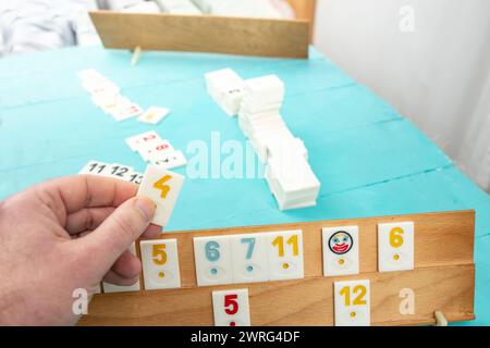Plastic tiles from the game rummikub, rummy or  okey in Turkey , scattered and arranged on  green background Stock Photo
