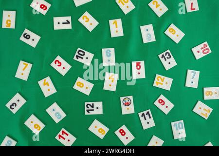 Plastic tiles from the game rummikub, rummy or  okey in Turkey , scattered and arranged on  green background Stock Photo