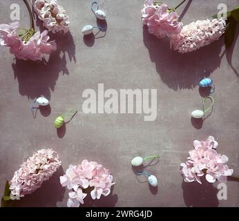 A group of pink spring flowers hyacinth and hydrangea sitting neatly arranged on top of a table with Easter eggs, copy-space. Stock Photo
