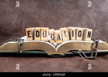Education word whiten with stamp letters on wood blocks, on a opened book with broken chains, representing education concept Stock Photo