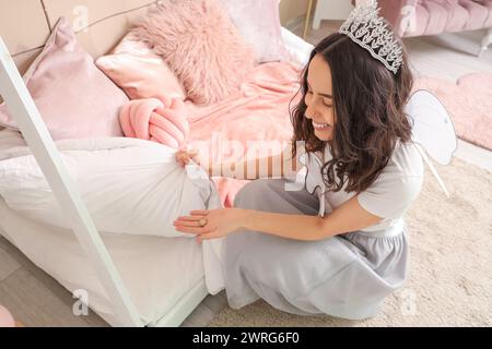 Tooth Fairy putting coin under pillow in children's bedroom Stock Photo