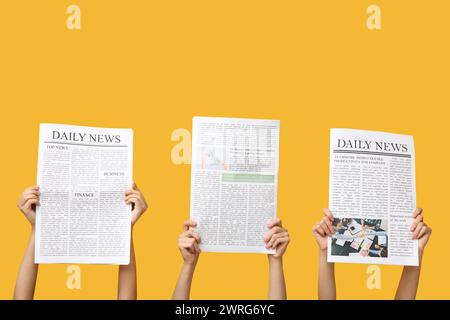 Women with newspapers on yellow background Stock Photo