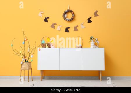 White wooden commode and Easter decor near color wall Stock Photo