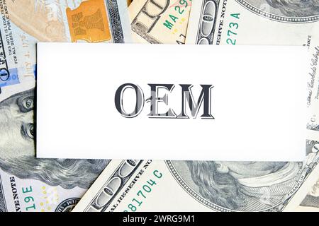 OEM original equipment manufacturer concept. Text on a white business card against the background of money, a business concept Stock Photo