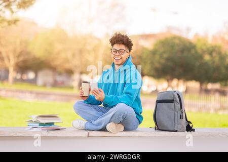 Brazilian university student enjoying coffee and using his smartphone outdoor Stock Photo