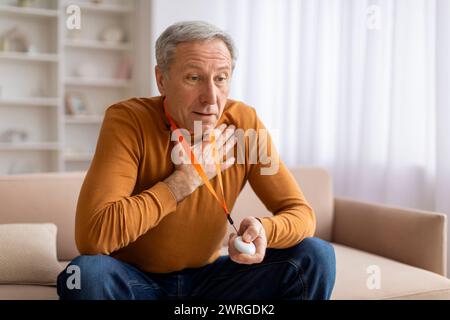 Anxious sick senior man pushing panic button on emergency equipment Stock Photo