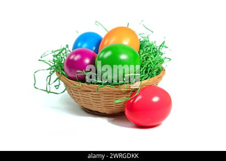 Colorful Easter eggs in a basket against a white background Stock Photo