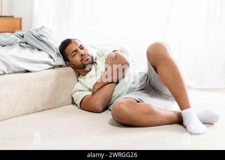 Devastated african american guy laying on floor at bedroom Stock Photo
