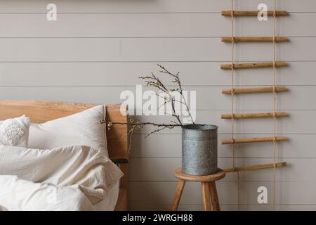 Vase with cherry plum branches on a bedside table next to an unmade bed in a bedroom Stock Photo