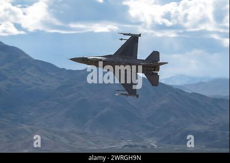 An F-16C Fighting Falcon assigned to the 706th Aggressor Squadron, conducts a familiarization flight over a low-level training area for Red Flag-Nellis 24-2, Mar. 7, 2024. Red Flag provides participants the opportunity to plan and employ together in the air, domain (supported by space, and cyber) in a contested, degraded and operationally limited environment. (U.S. Air Force photo by William R. Lewis) Stock Photo